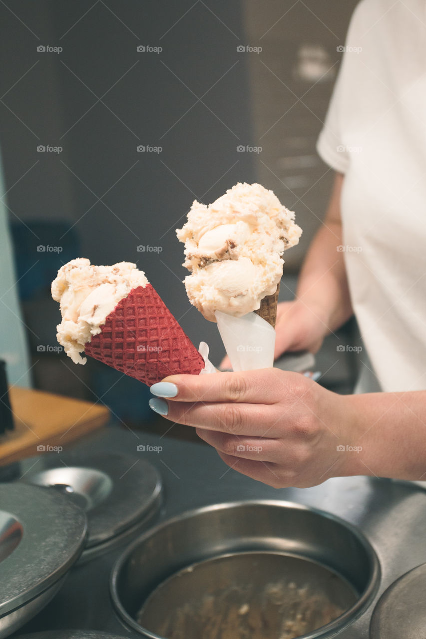 Seller selling couple scoops of  ice cream in a candy shop by a street. Woman putting a scoops of ice cream to a cones