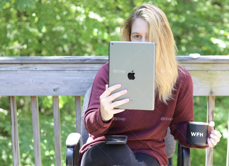 Quick Meeting Outdoors using a Gen 7 iPad; Woman Holding iPad and “Work From Home” cup, iPhone 11 Pro Max on Knee