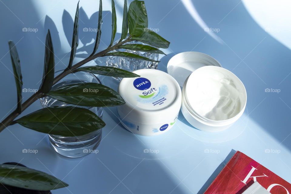 Nivea skin care product on a blue background with a green flower.