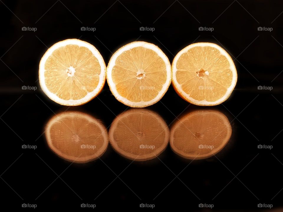 yellow lemon slices on black glass background