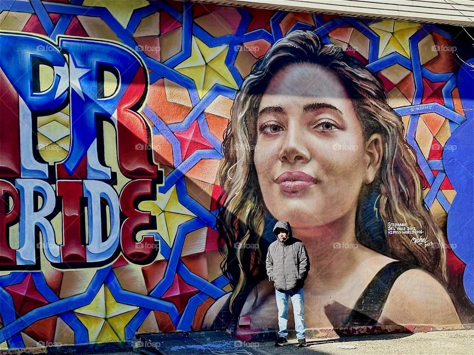 This is one half of a very large art mural on „Jefferson Street“ off „Broadway“ in „Bushwick“, Brooklyn containing the word „PRIDE“ and the portrait of a beautiful young hispanic lady from NYC. 2024. Hypnotic Productions