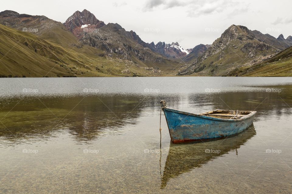 Blue rowing boat. Old blue rowing boat on mountain lake. Andies in the background. Clouds and glacier. 