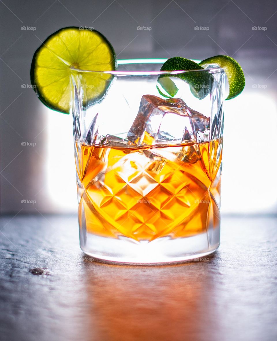 A drink on ice in a frosted glass with a twist and slice of lime