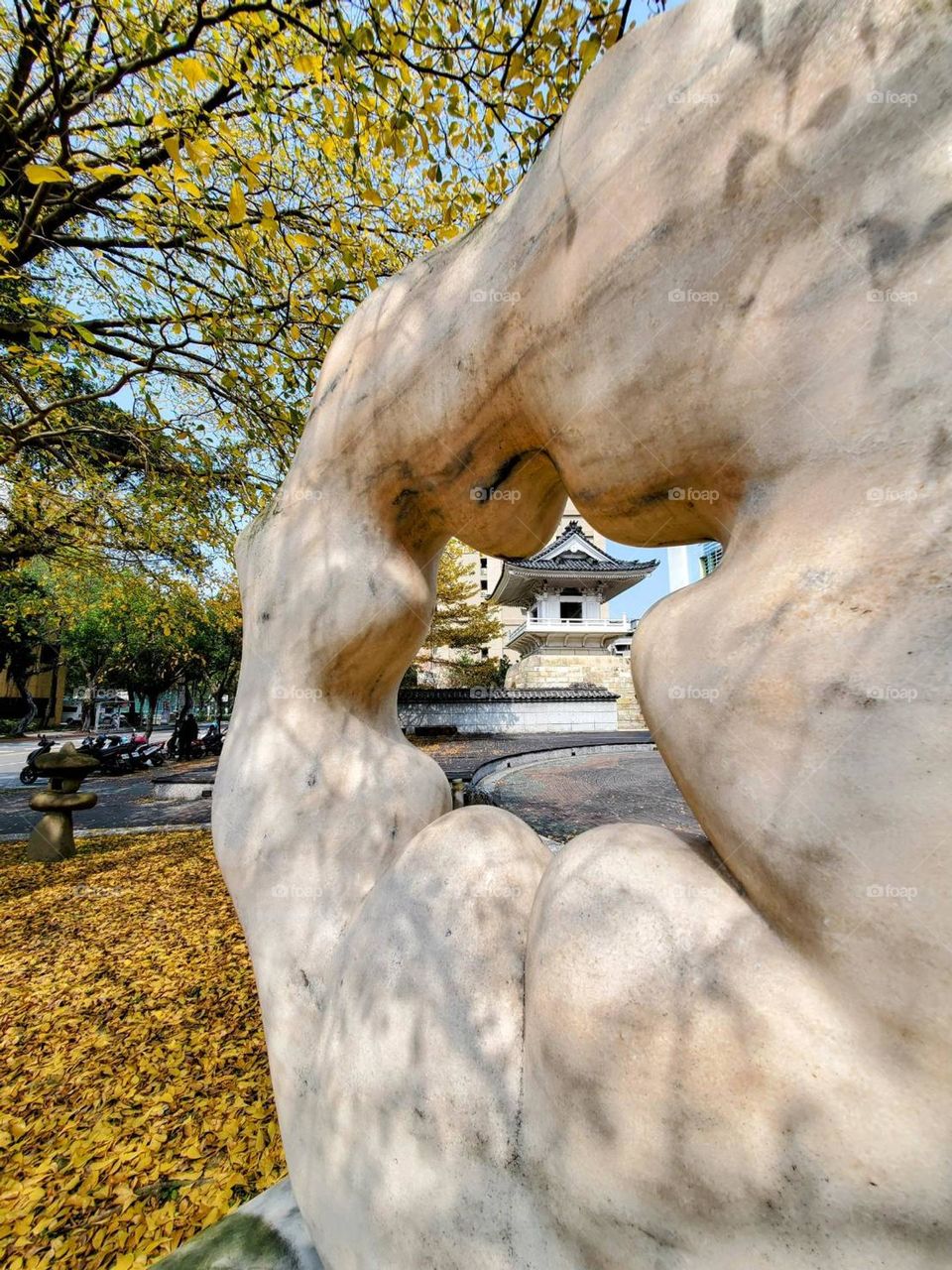 Through the carved art cave, you can see the bell tower of the Japanese temple and the brilliant autumn leaves on the ground.