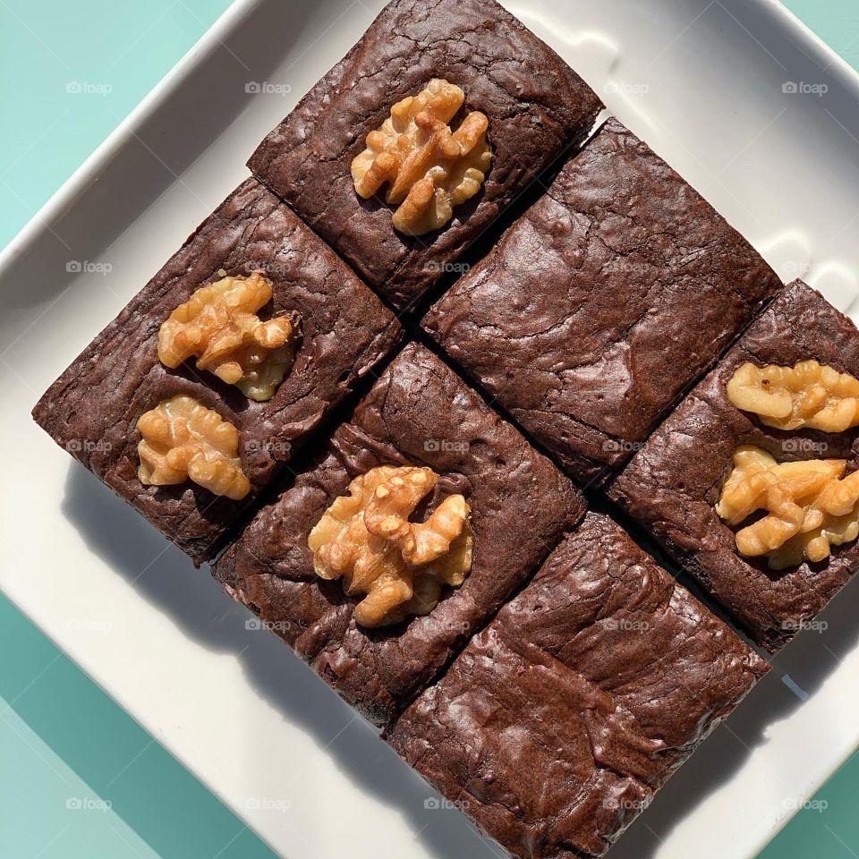 Plain original brownies and walnut brownies put together on white glass plate 