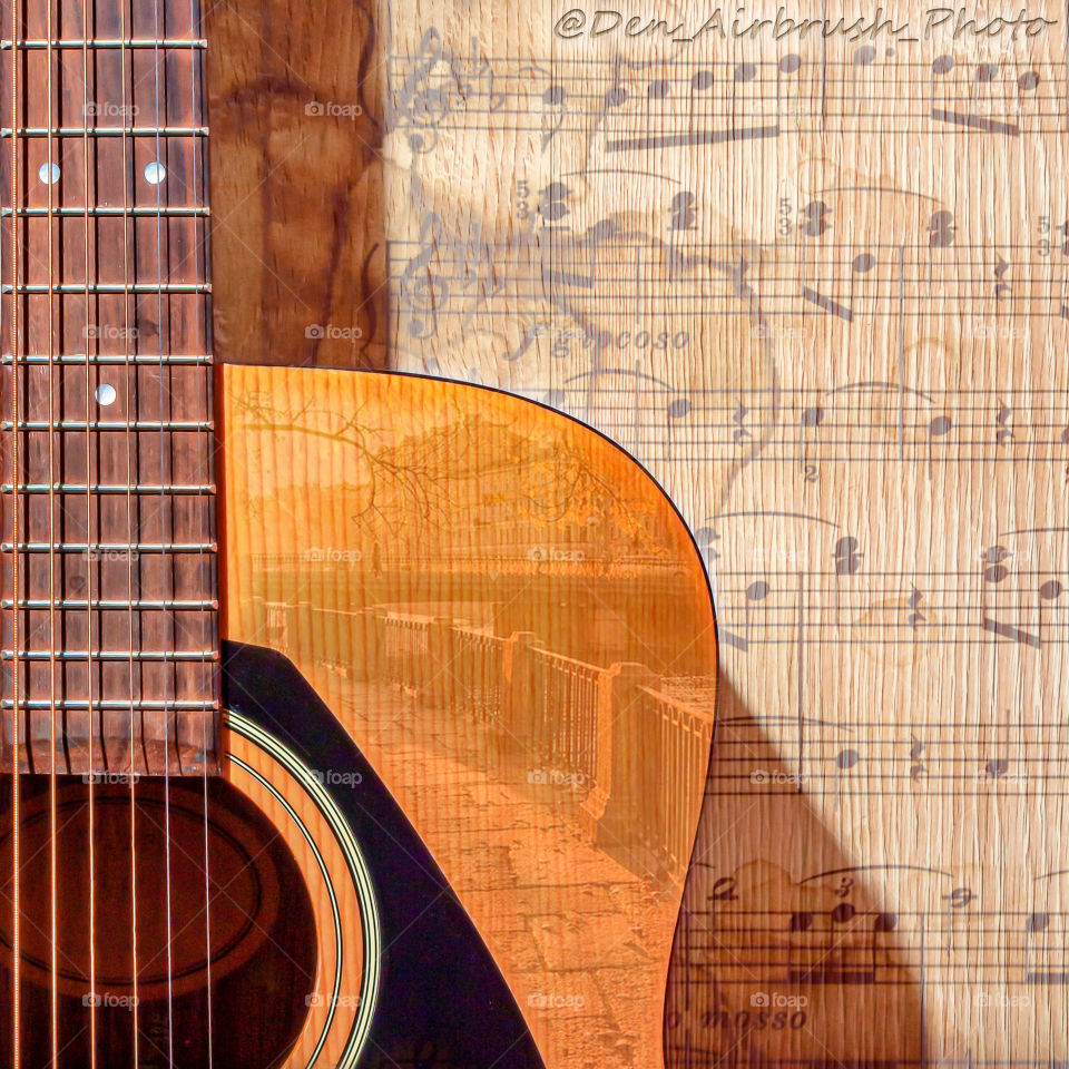 Classical acoustic guitar with silver strings and a view of the city on a wooden background with notes and texture.