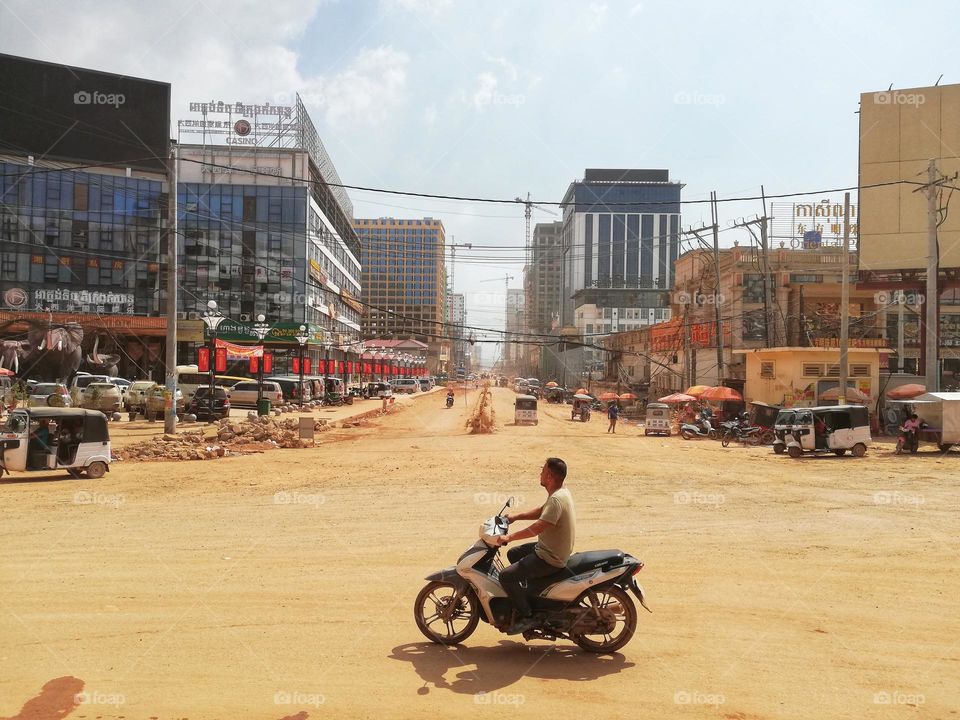 man on scooter runs through the dusty city of Sihanoukville