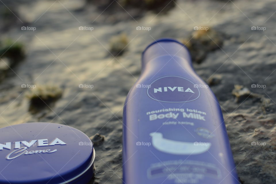 Nivea creme and Nivea body lotion are flaunted on the sea rock covered by beautiful Leathesia or Marine algae.