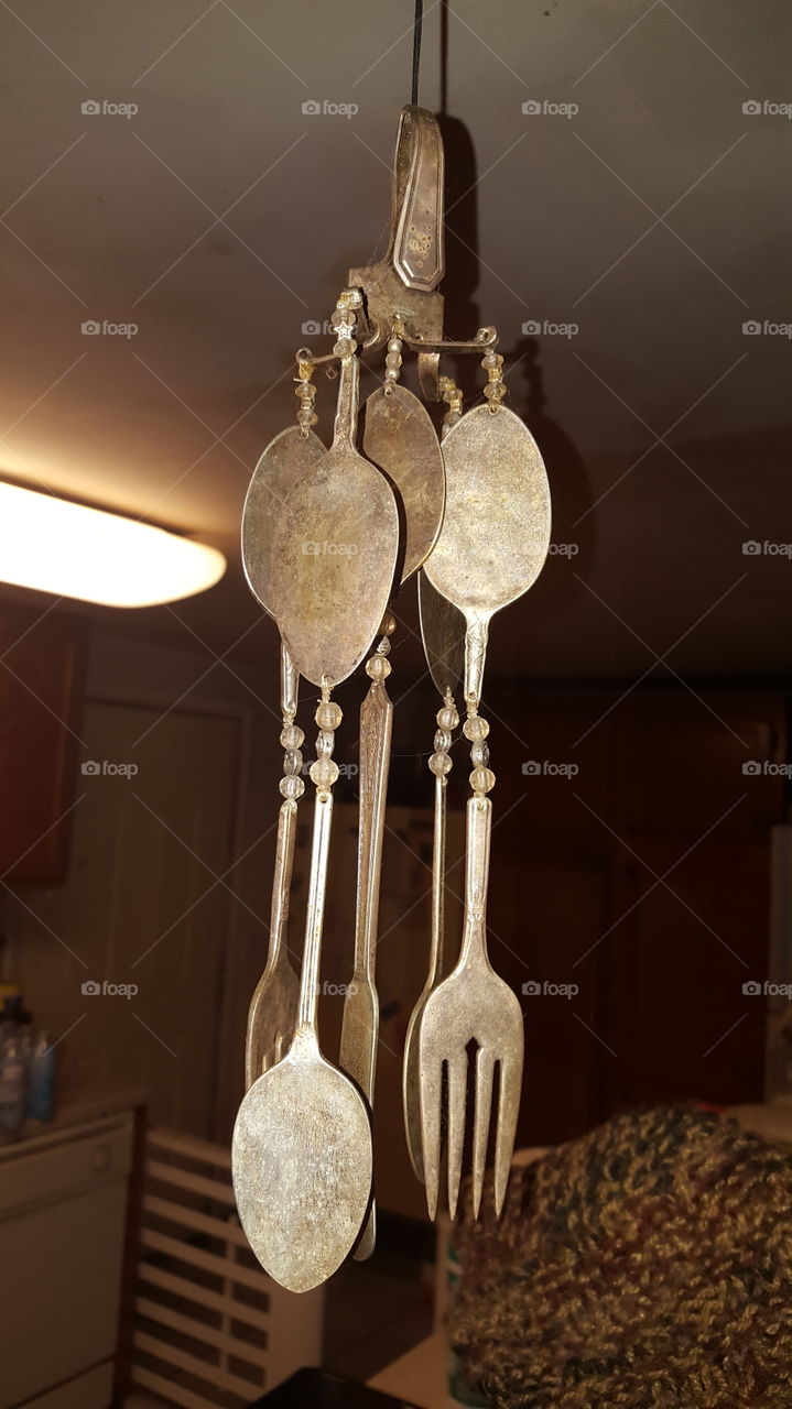 I don't know how old this silverware windchime is but it's silver and is hanging from the kitchen ceiling.