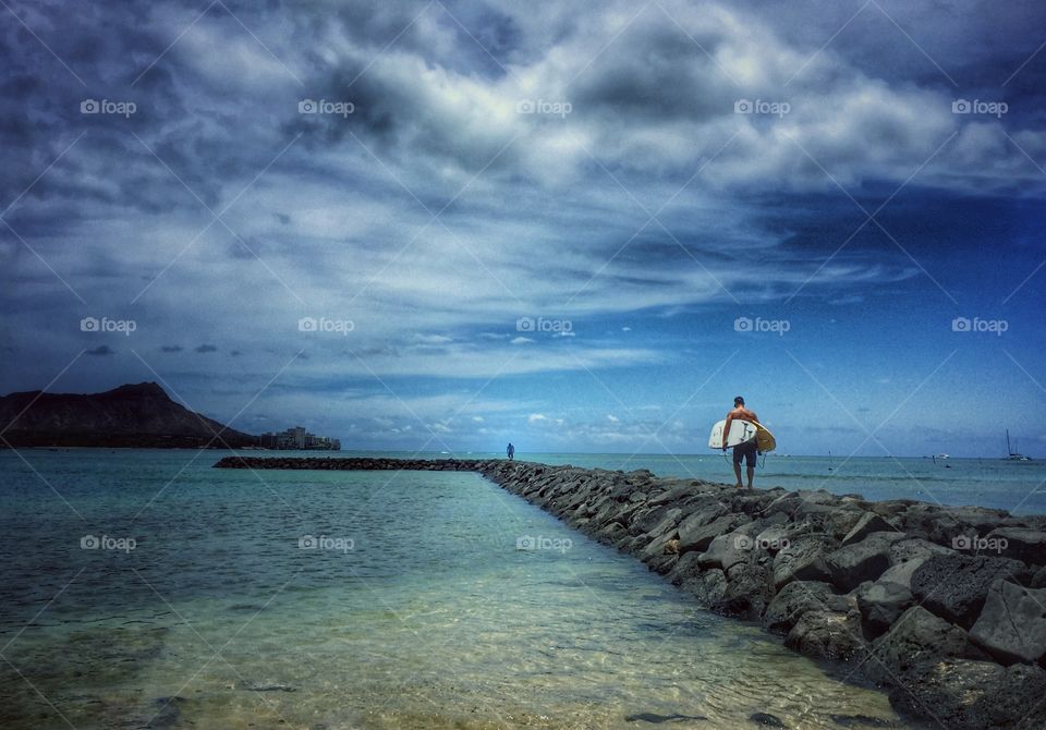 Carrying surf boards on stone jetty near Diamond Head
