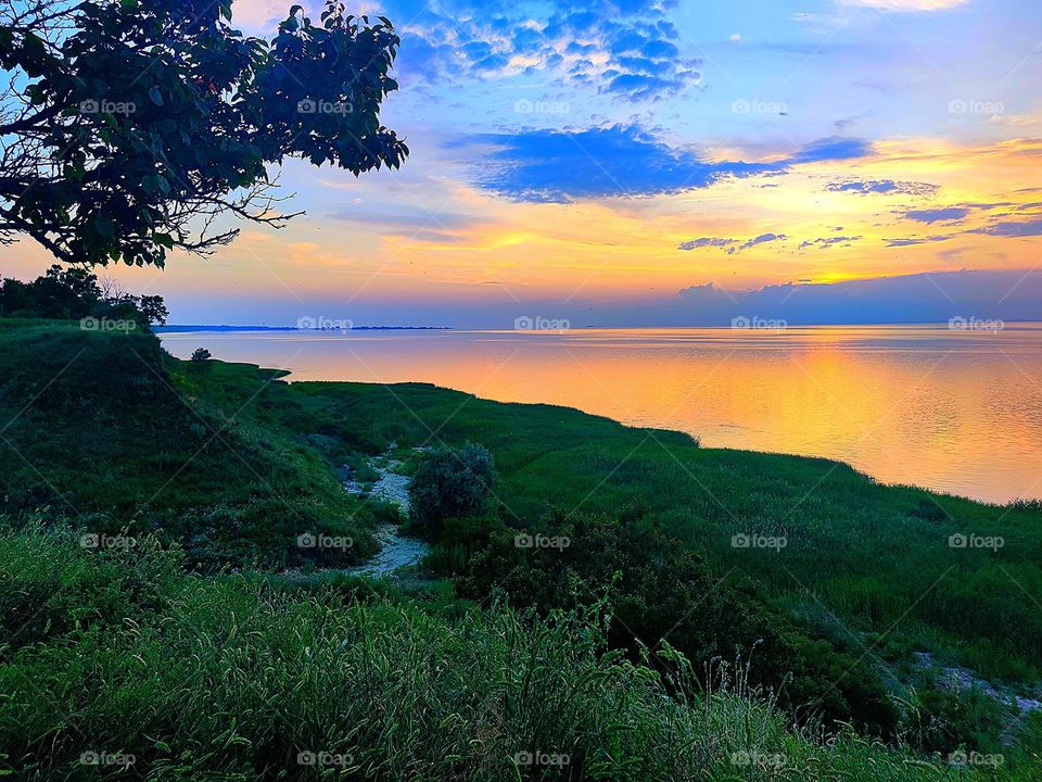 Summer.  Sunset on the sea.  View from the green cliff