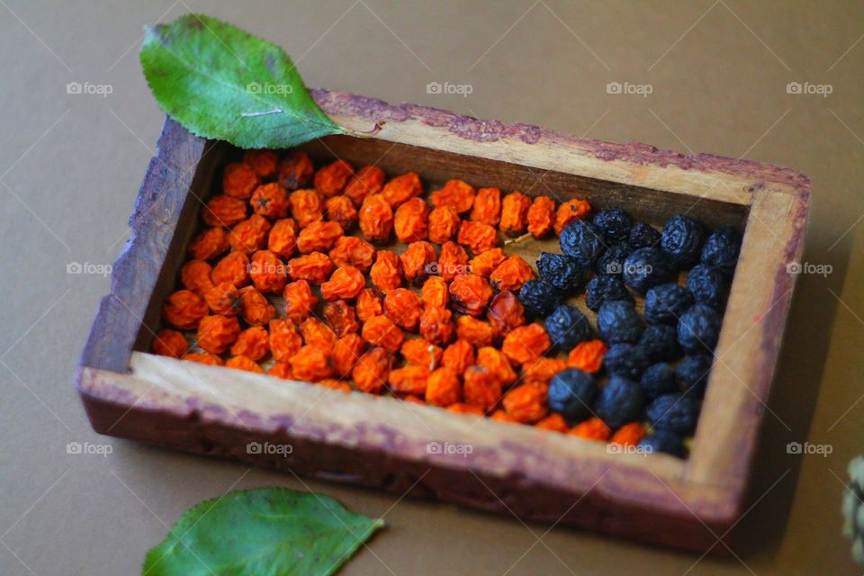 in a small wooden rectangular box are dried rowan and currant berries