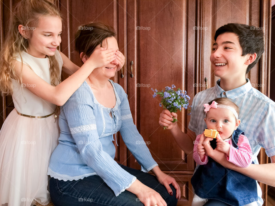 Children giving surprise gift to their mother on birthday