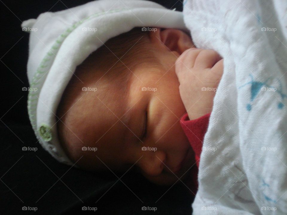 Baby wearing a white hat sleeping.