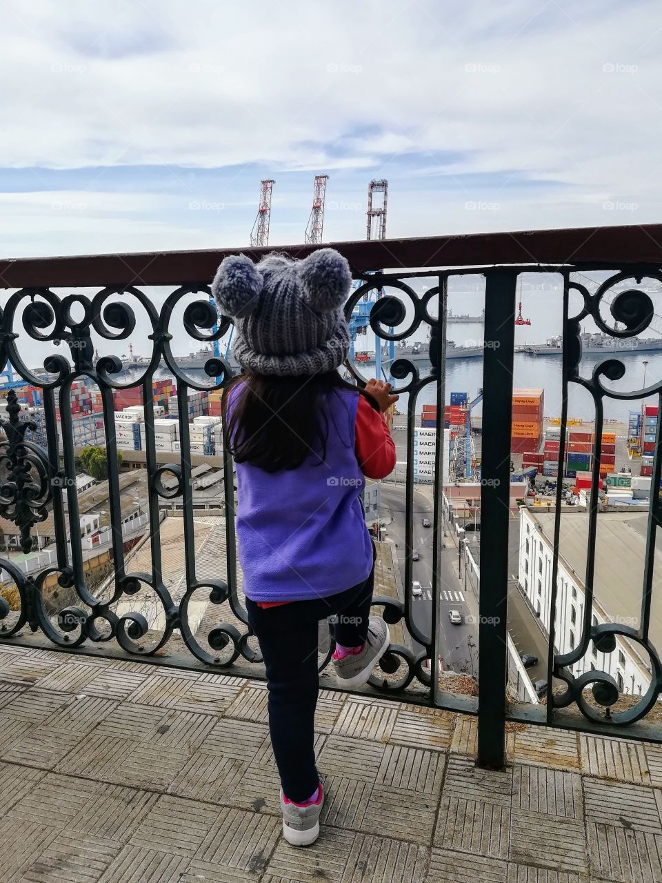 My daughter Salome contemplates the beautiful view from the artillery hill in Valparaíso, captivated by the pier and its large ships and colorful containers