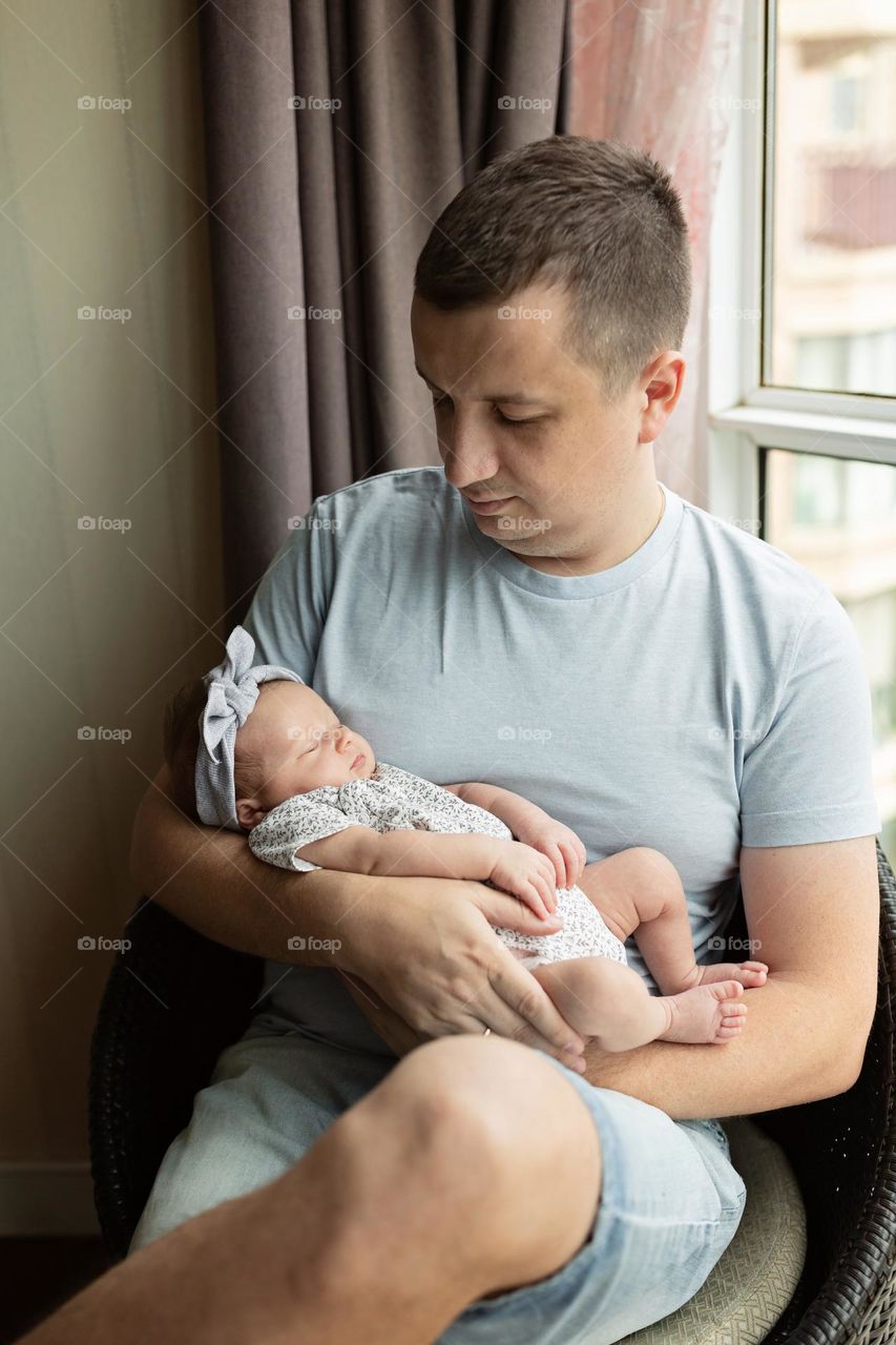 Happy father holding his newborn daughter at home