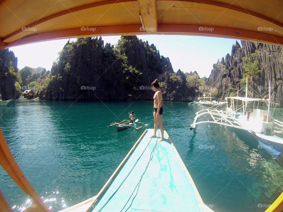 Lady standing at the edge of the boat, boatman sailing, at a beautiful twin Lagoon in Coron Islands, Palawan, Philippines