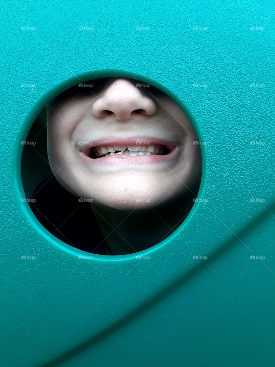 Kid smiling through playground equipment