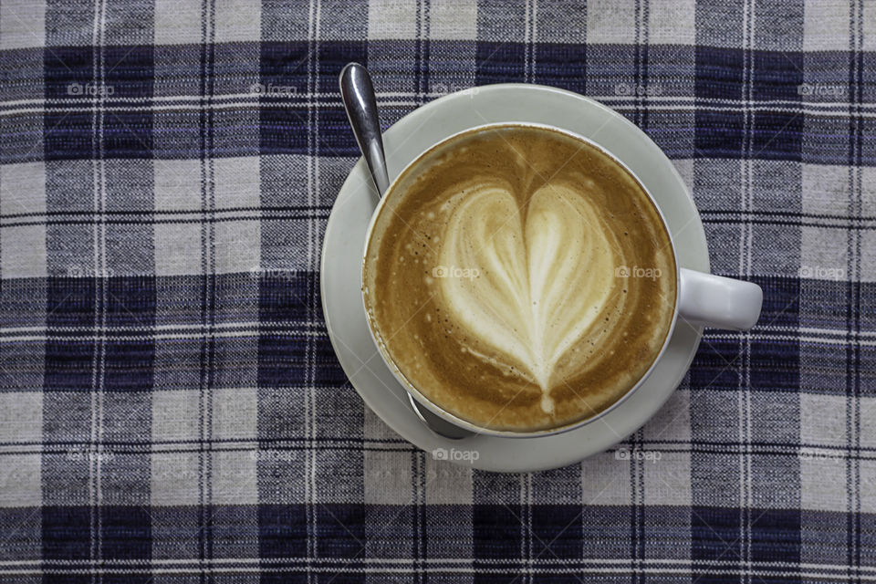 Hot coffee Espresso topped with a heart-shaped milk in white glass On the table with chintz Scott.