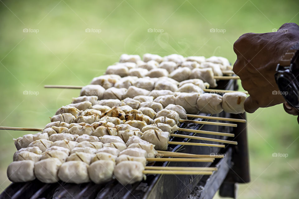 Grilled pork meatballs on the grill , charcoal is on fire.