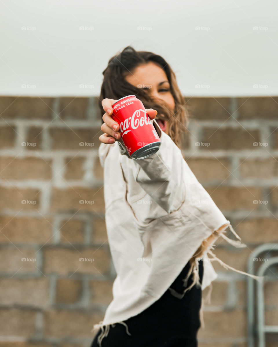 Girl showing a coca cola can with a big smile.