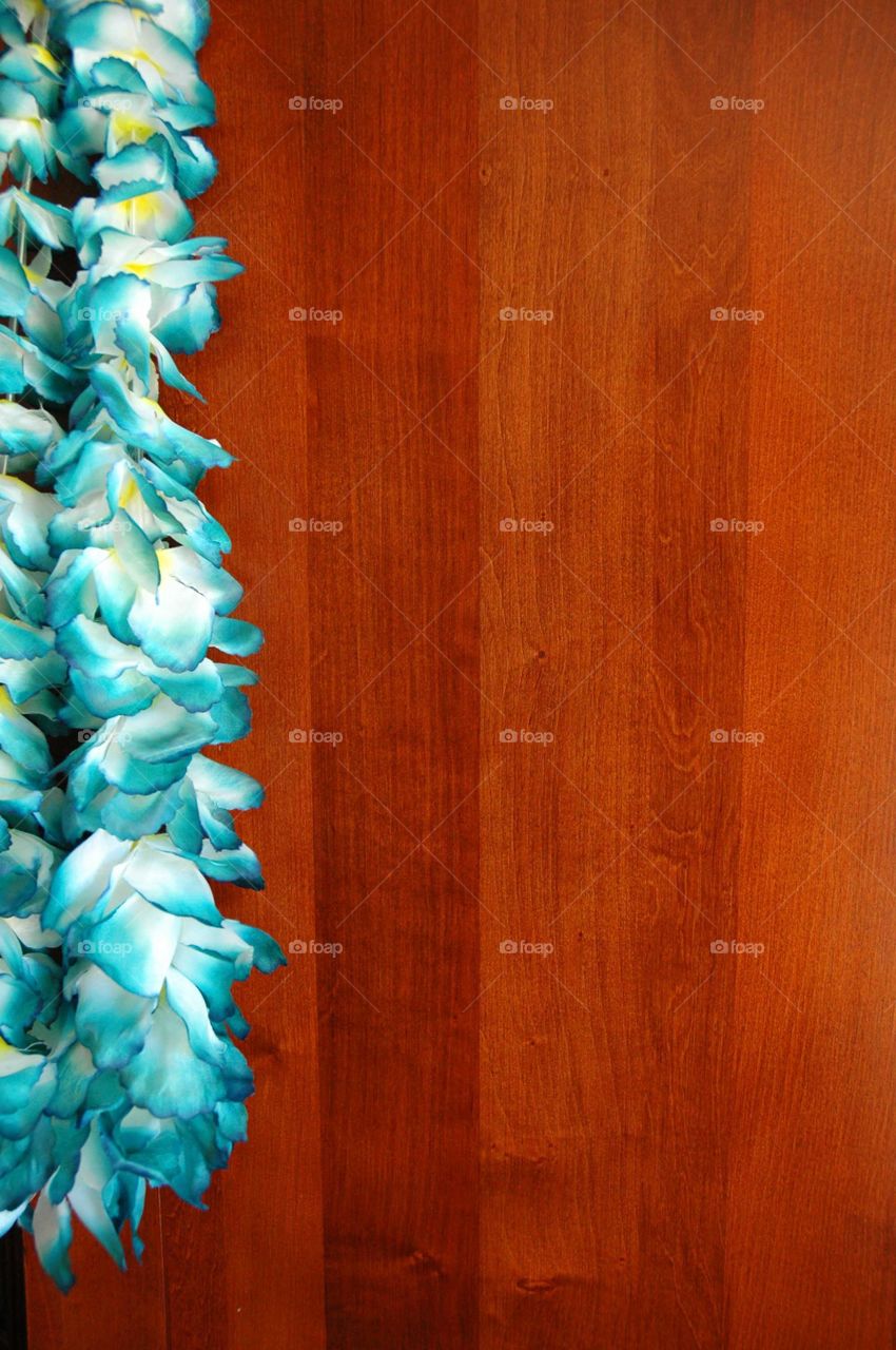 Ready for your tropical vacation. Blue lei hanging on a door, room for your copy. 