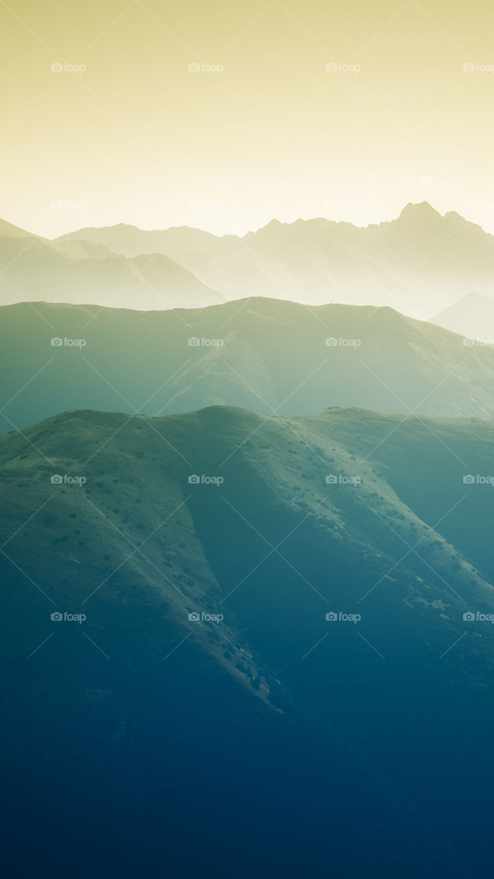 An inspiring mountain landscape. Tatry mountains in Slovakia. A beautiful wallpaper for smartphone screen. Warm summer haze, abstract gradient with perspective.