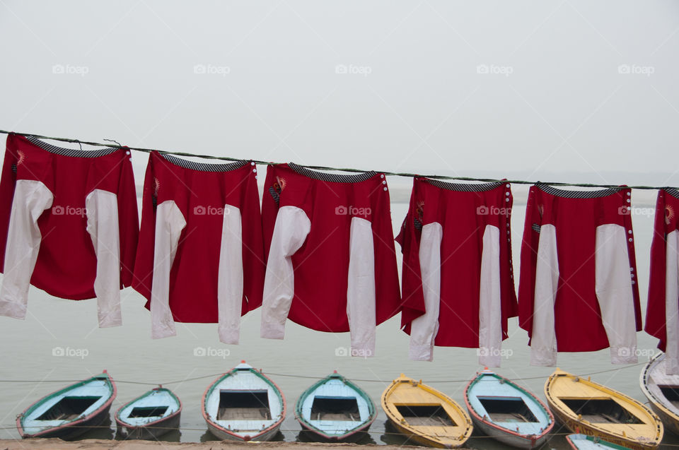 Red and white school jackets on washing line on the ghats in Varanasi, India