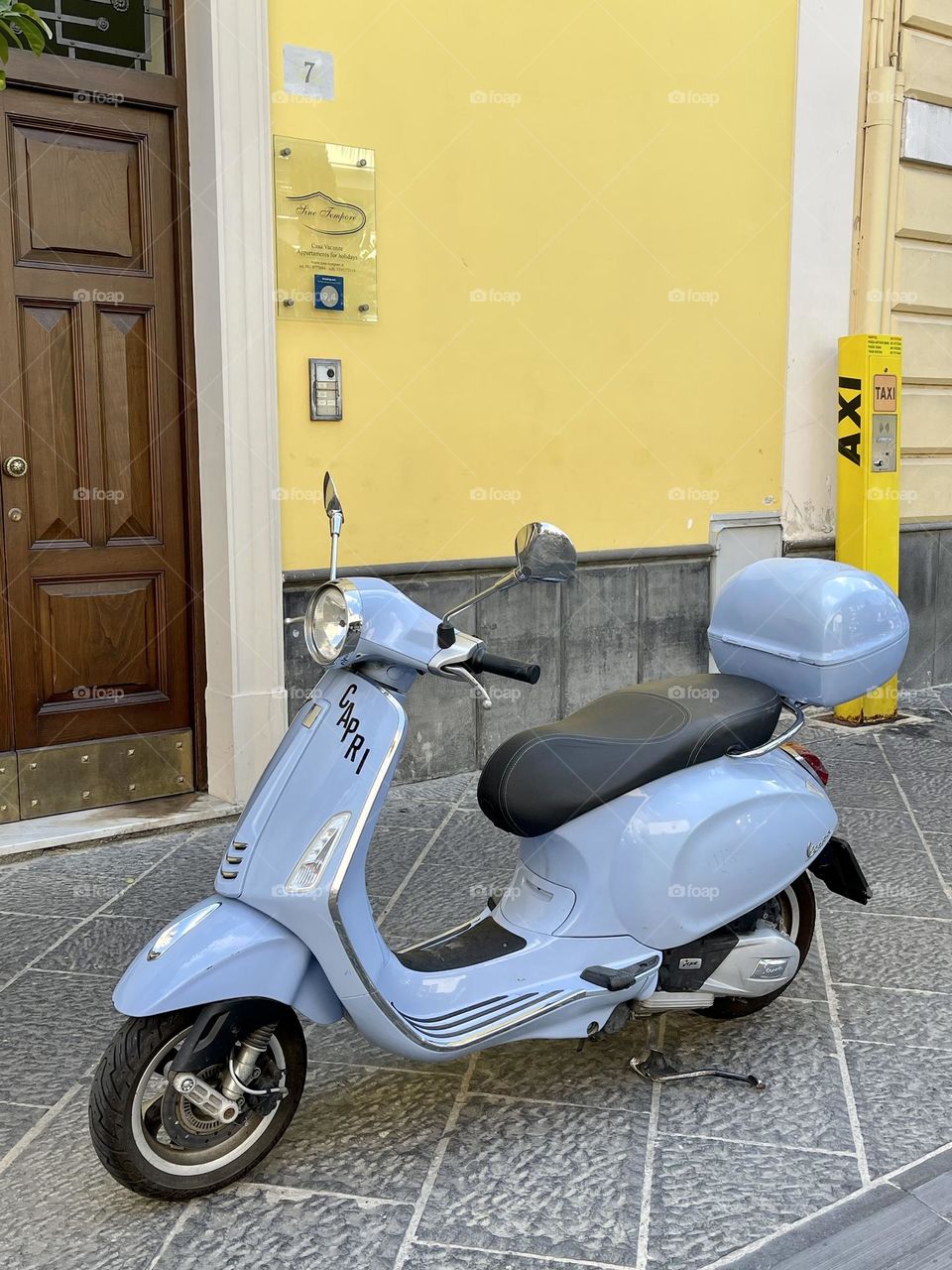 Blue scooter on the yellow wall background 