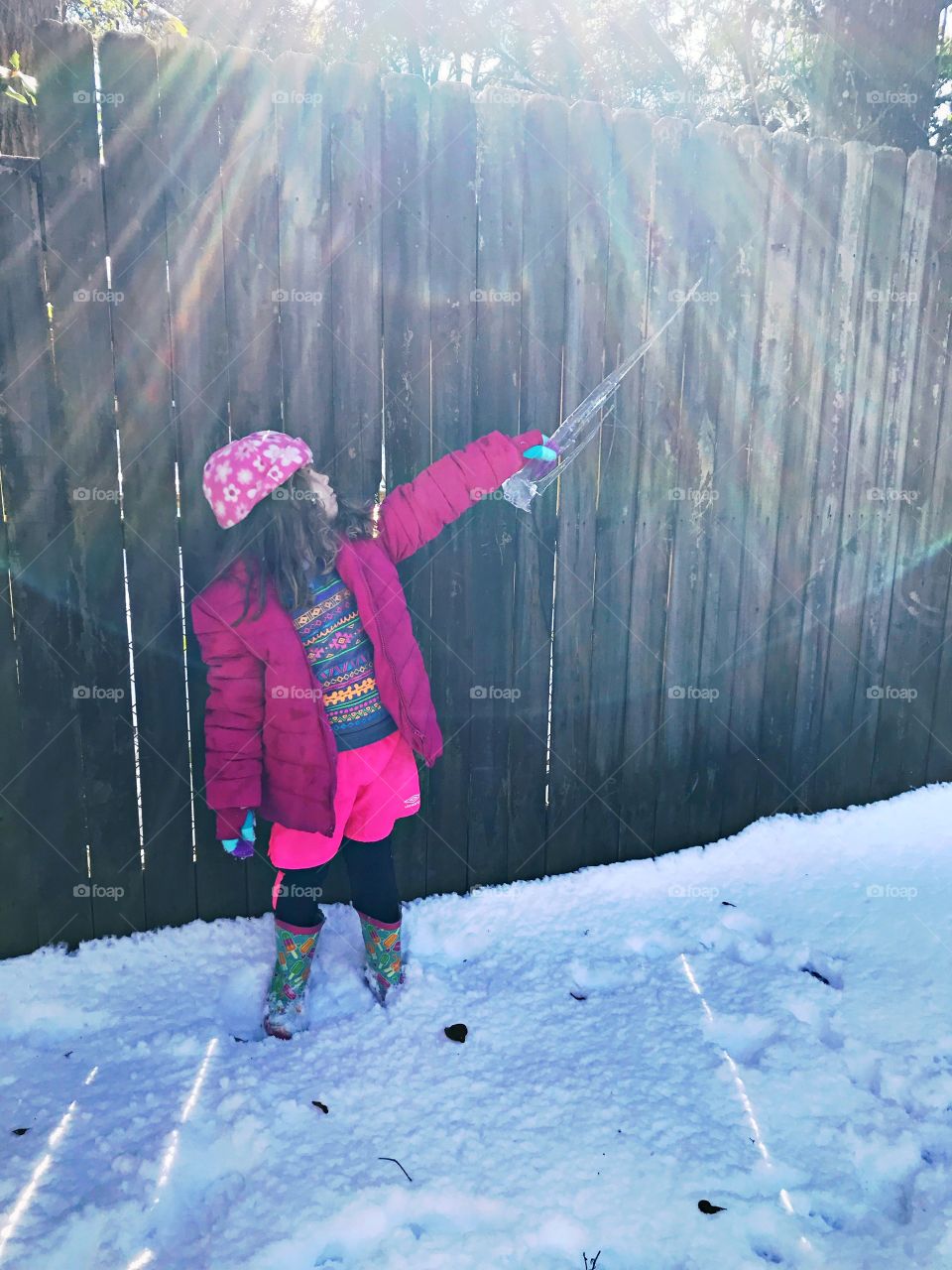 Girl plays with icicle in the snow  
