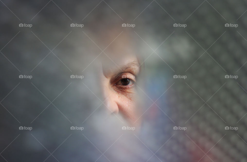 Woman looking in a hole of plastic bubbles, looking at camera