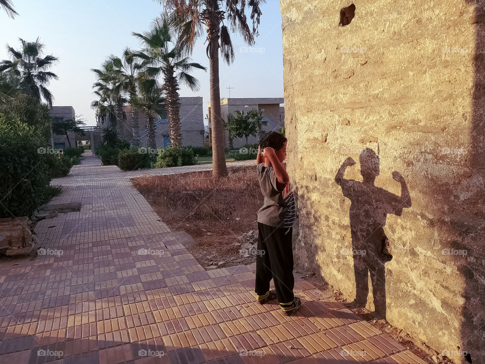 A kid look like the superhero shadow under the sunlight.
