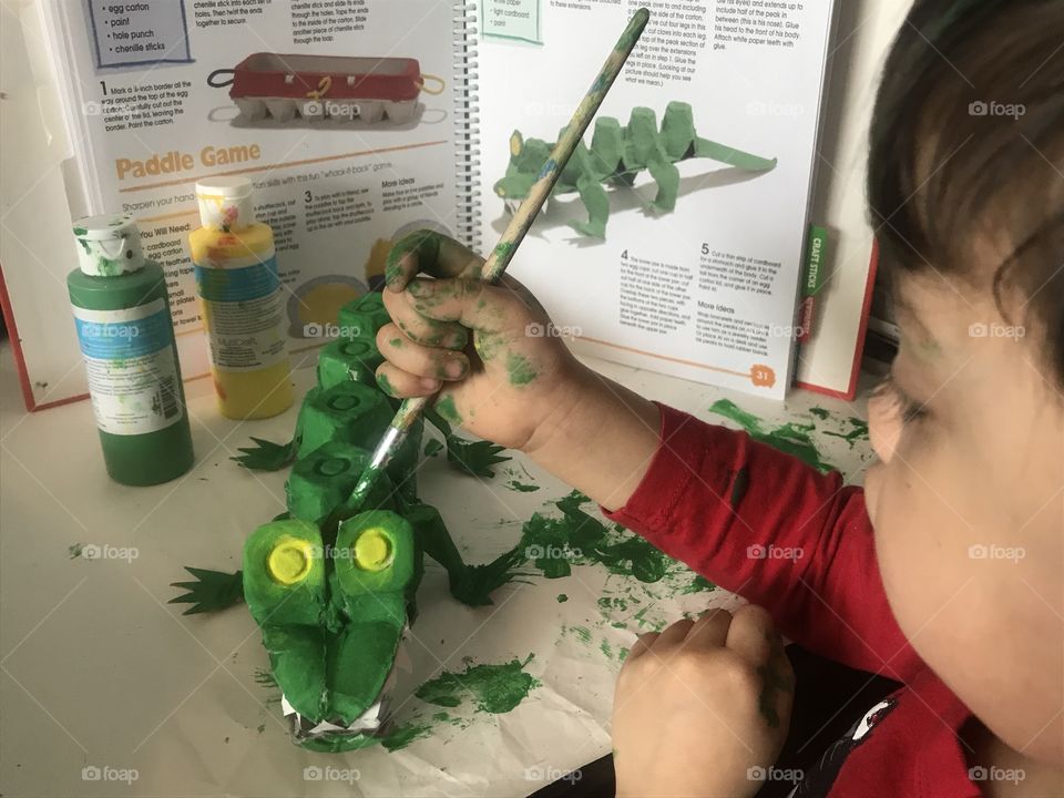 Young boy painting an alligator craft