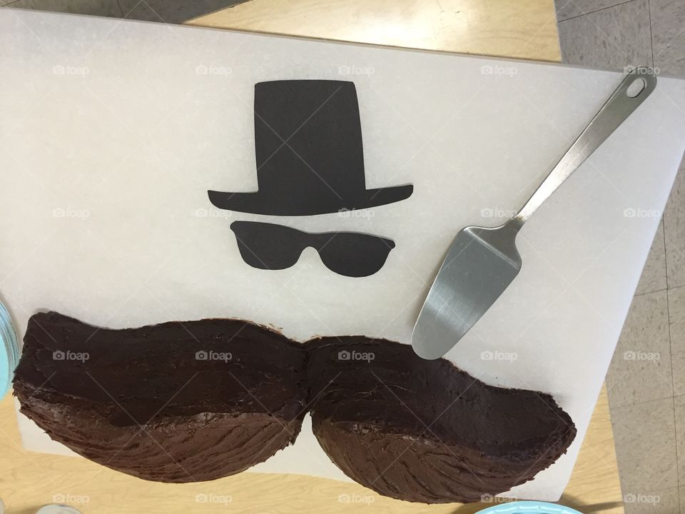 Baby shower chocolate cake with top hat and mustache representing woman having a boy.