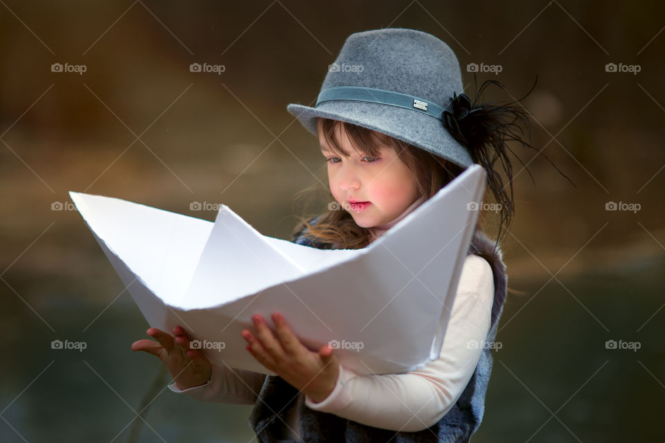 Little girl with paper boats at spring river