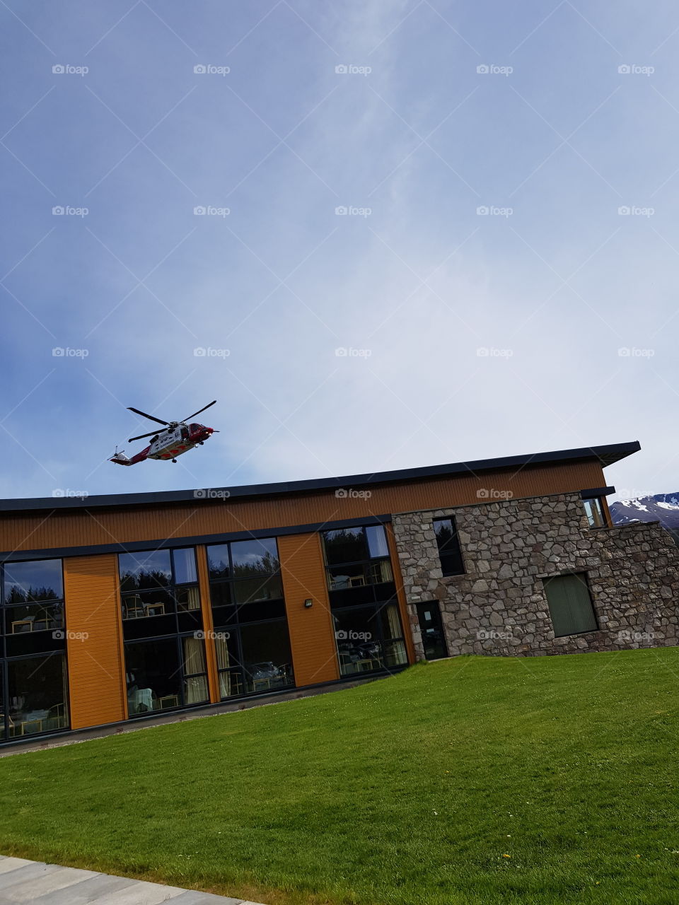 Rescue helicopter coming into land over brightly coloured building.