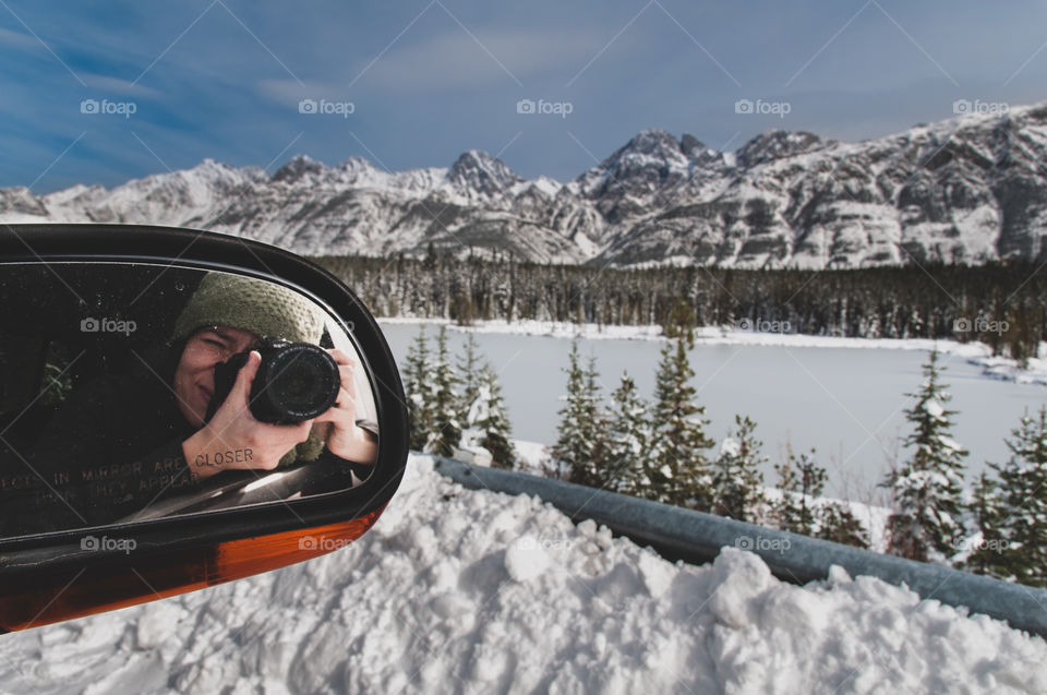 self portrait woman taking pictures from car against snowcapped mountains