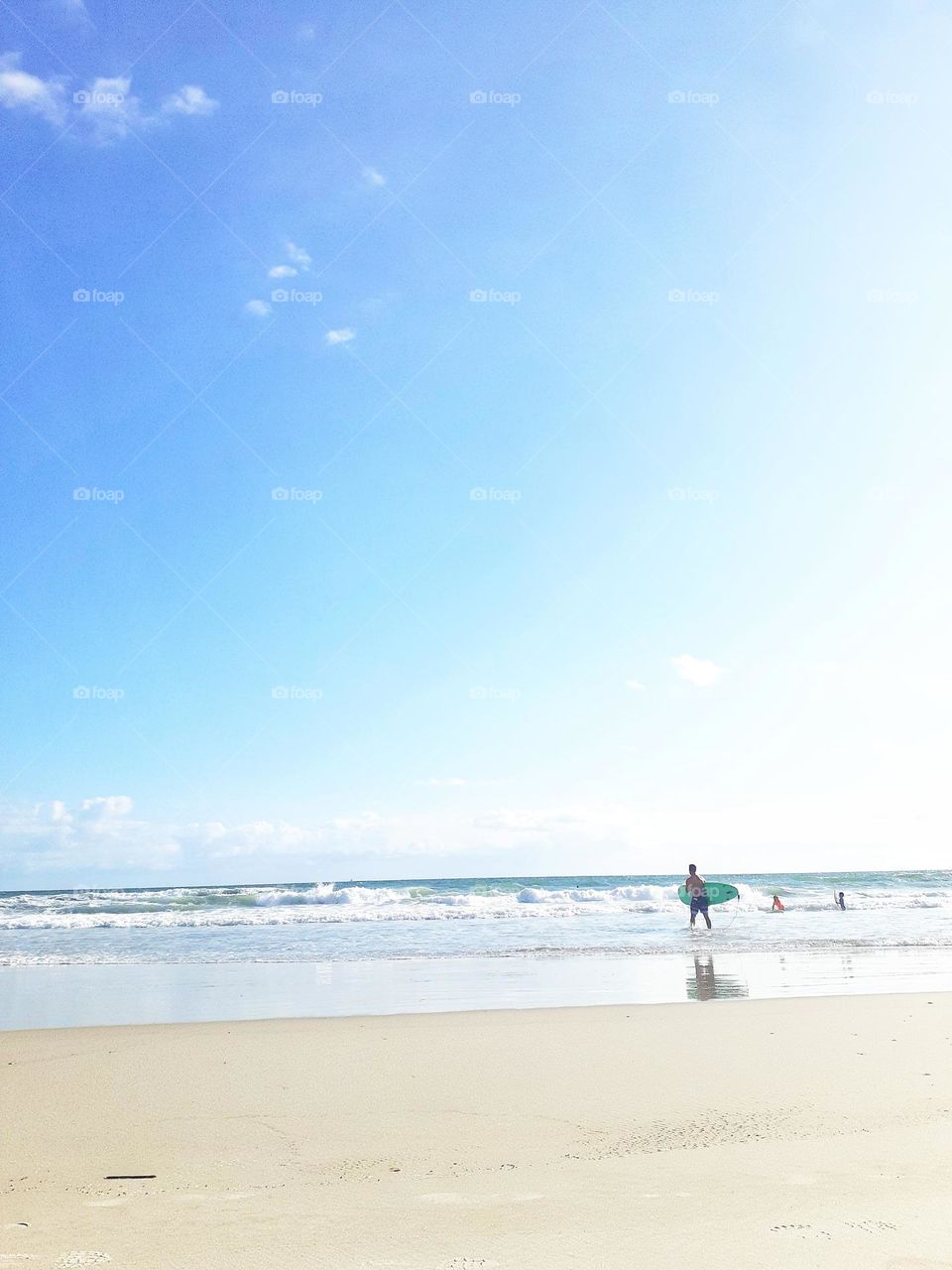 A surfer carries his surfboard into the ocean to go surfing at Indian Rocks Beach.