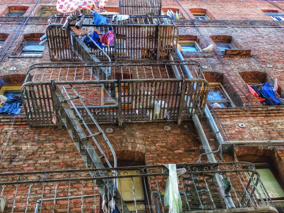 Drying Laundry Hanging From Windows Of Tenement Apartments. Highrise Fire Escape
