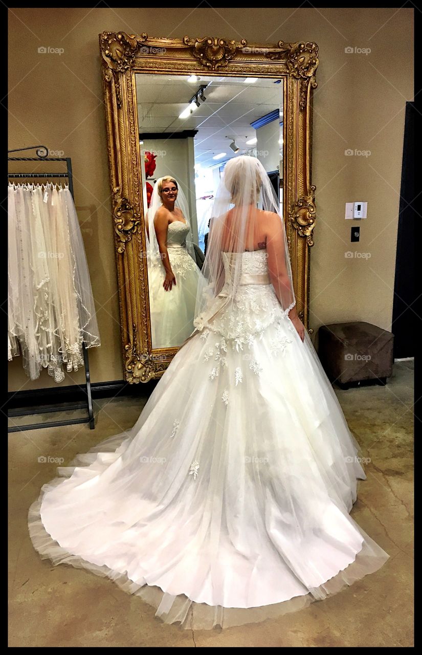 Girl trying on wedding dress. Bride. Mirror 
