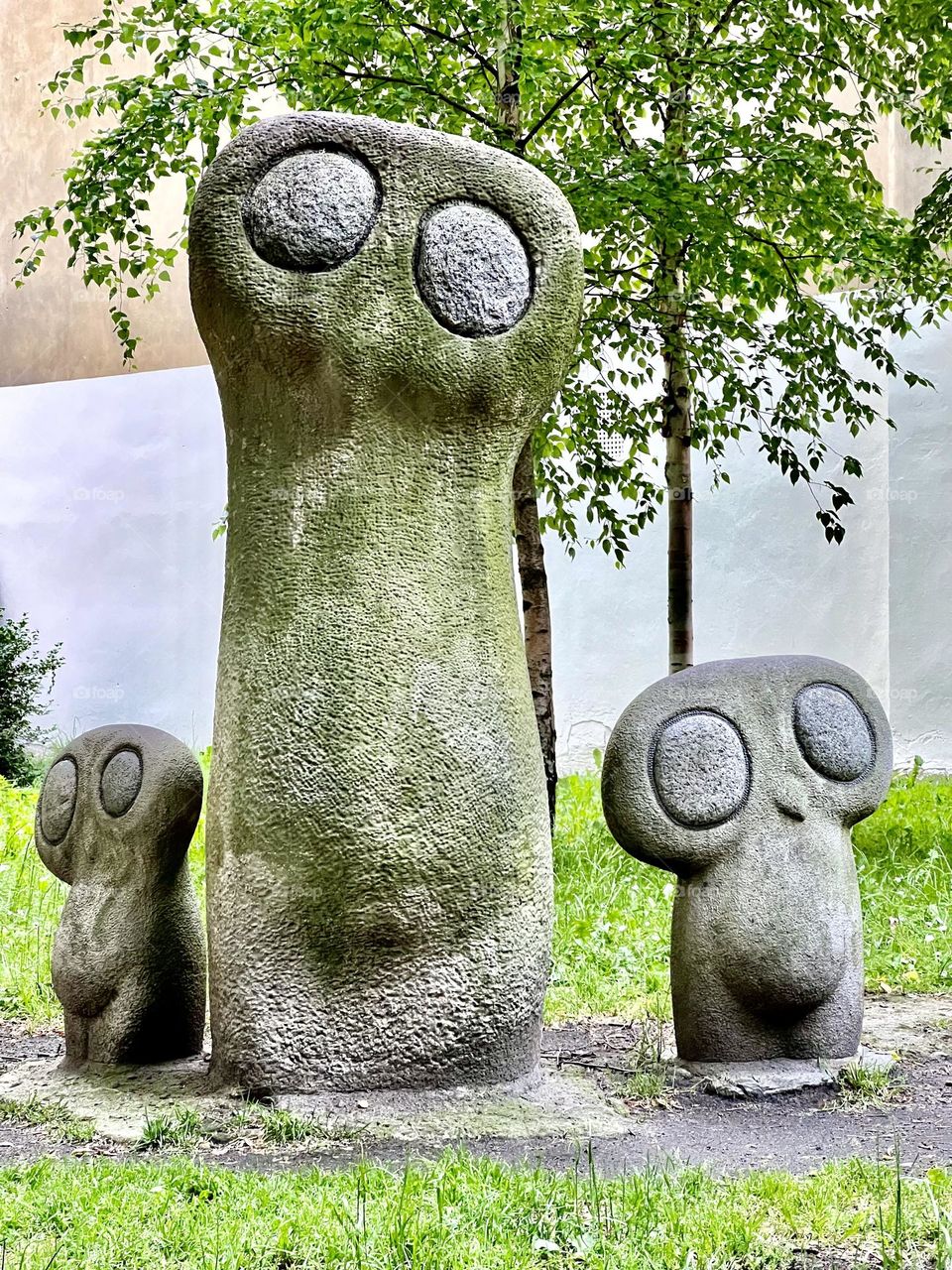 Sculpture "Owl" in Krakow. One is tall, and on either side of it are two smaller ones. they are carved from sandstone with granite eyes.