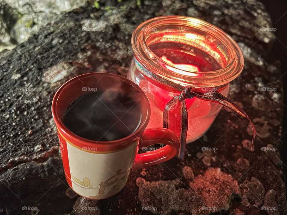 Steaming hot spiced wine at the Christmas market with a winter candle standing on a wall.