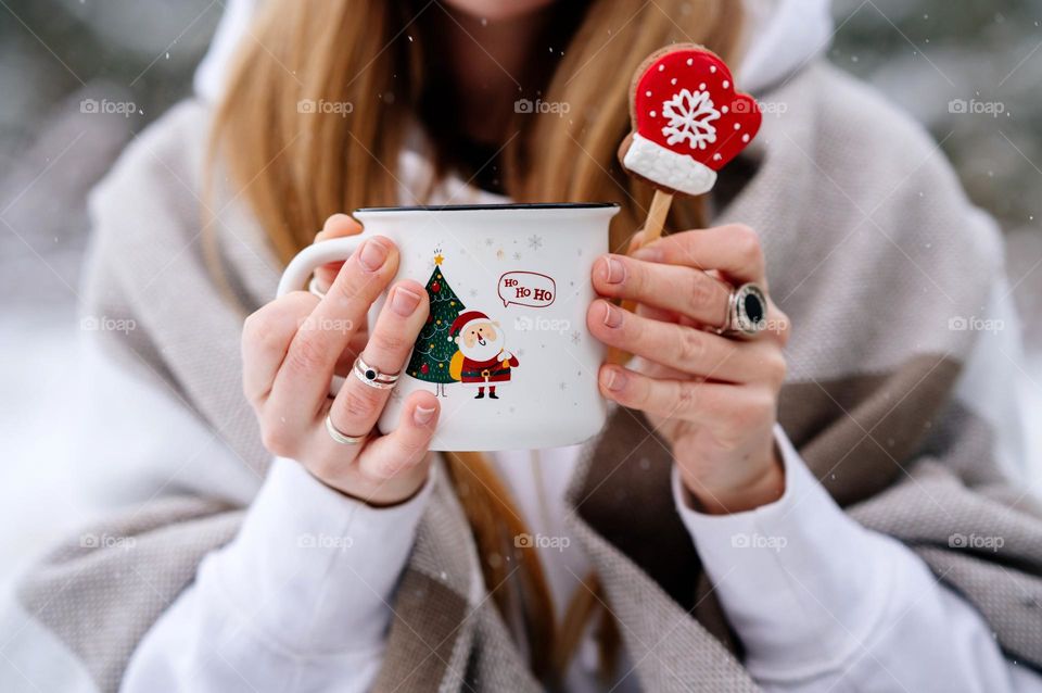 Woman holds white mug with Christmas print. Holiday mood. Hot beverage