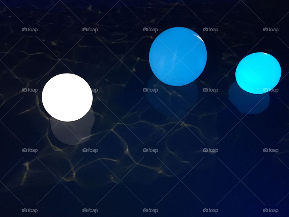 Balls Ligh in swimming pool . Blue and white balls of light reflecting water 