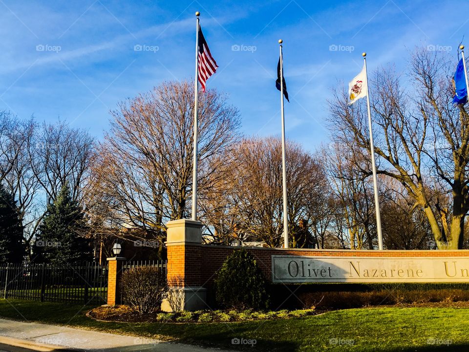 Flags fly straight in  brisk winds over Oliver Nazarene College campus