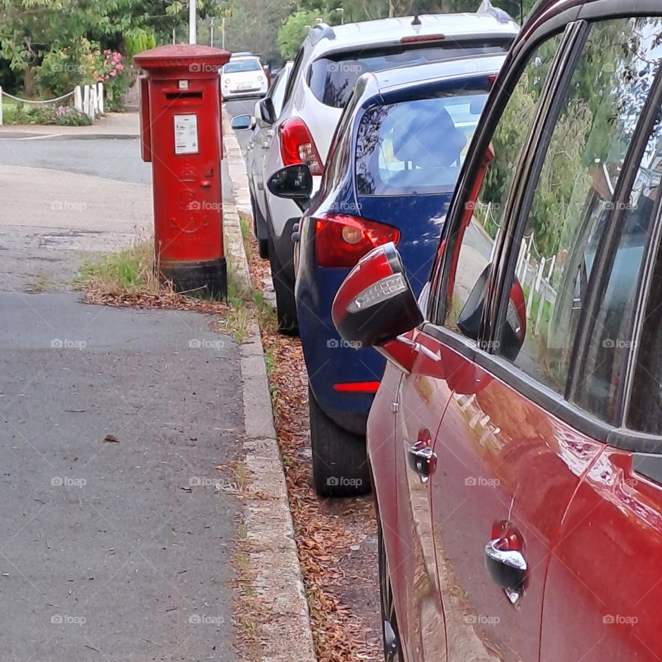 street view line of cars red white blue. red postbox in pavement.
