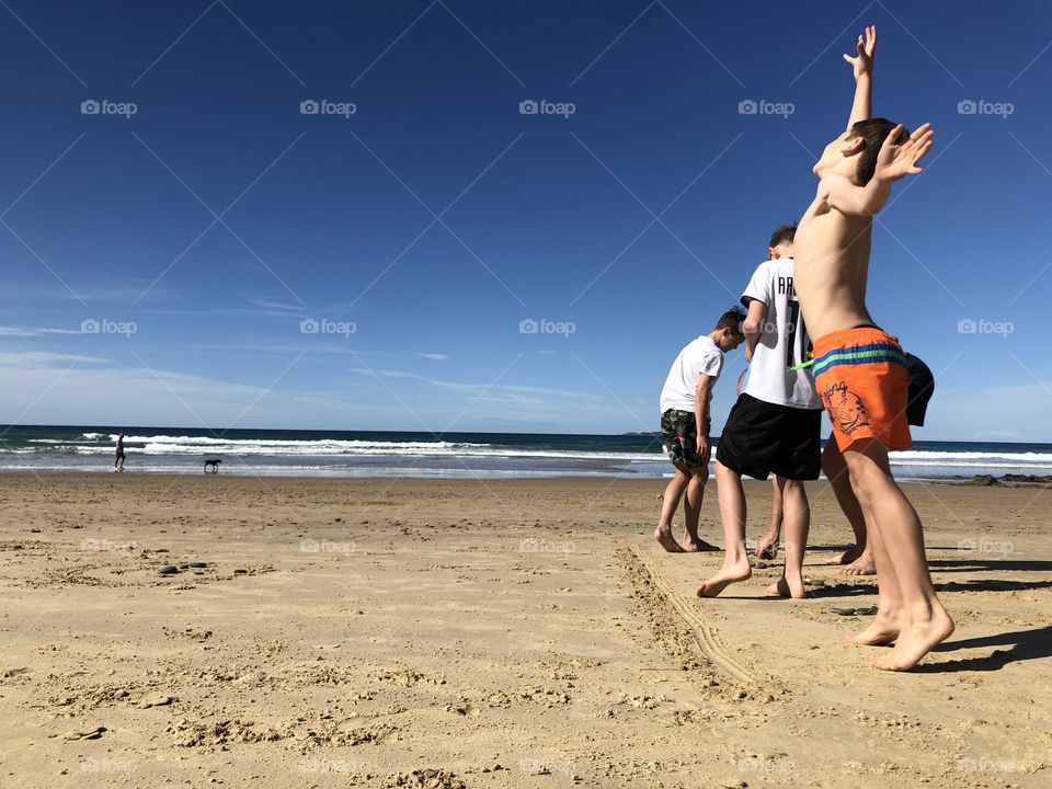 Playing a stone throwing family game on the beach and jumping with victory. Standing in a line on the beach on a sunny day. 