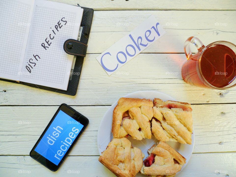 homemade cake, a cup of tea, a smartphone and a notebook on the table