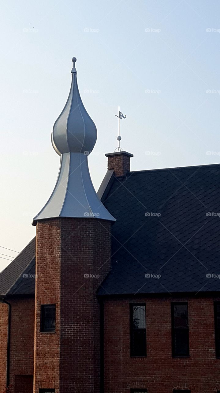 Brick church turret with white sculpted roof dome.