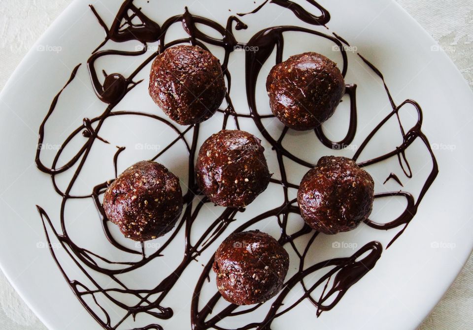 More Chocolate - Nut Butter Cocoa Bites on white plate with chocolate drizzle flat lay